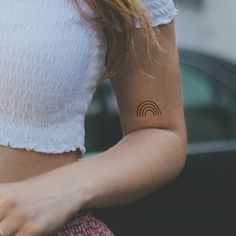 a woman with a small tattoo on her left arm holding a cell phone in her right hand