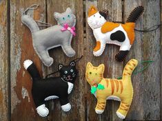 four felt cat ornaments hanging on a wooden fence