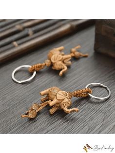 two wooden keychains with elephants on them sitting on a table next to a bottle opener