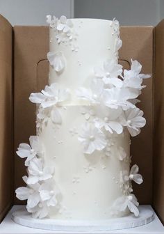 a white wedding cake in a box with flowers on it's top and bottom