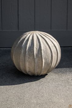 a cement ball sitting on the ground in front of a garage door with a black wall behind it