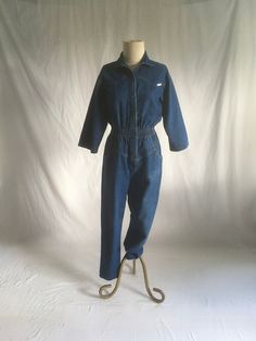 vintage 80s women's denim jumpsuit label- Dreams cotton blue jeans wide smocked elastic waist chevron chest 2 hand pockets tapered leg good vintage condition, light wear a few faded stains, light collar ring fade, knee fade (see photos) labeled size medium, see below measures, lying flat, shoulder-17" chest-18" sleeve-16" waist-13" to 15" stretched comfortably hip-19" rise-15" inseam-27" hem-6" top to waist-19" waist to hem outseam-41" total length-59"     We do not offer returns or refunds unle Blue Jean Jumpsuit, Womens Denim Jumpsuit, Jean Jumpsuit, 80s Women, 80s Denim, Womens Jumpsuits, Pink Doll, Jeans Wide, Jeans Jumpsuit