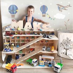 a young boy standing in front of a wooden shelf filled with toys