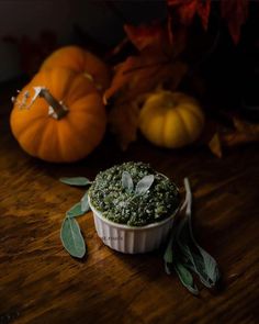 a small white bowl filled with food on top of a wooden table next to pumpkins