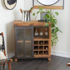 a wooden cabinet with wine glasses on it in front of a mirror and potted plant