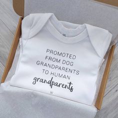 a baby's shirt in a cardboard box with the words grandparents printed on it