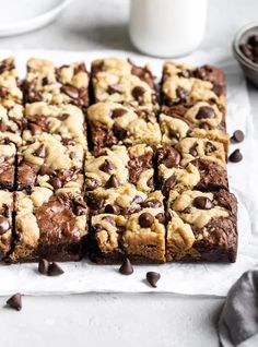 chocolate chip cookie bars cut into squares on top of parchment paper next to a glass of milk