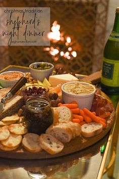 a platter filled with bread, crackers, and vegetables next to a bottle of wine