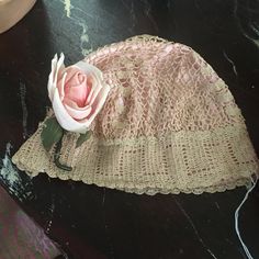 a pink rose sitting on top of a lace doily next to a flower pot