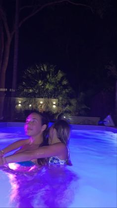 two women are in the pool at night