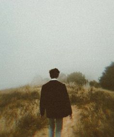 a man walking down a path in the middle of a field