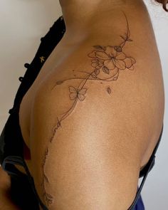 the back of a woman's shoulder with flowers and leaves on her left side