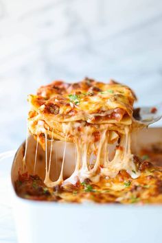 a spoon full of lasagna being lifted from a casserole dish