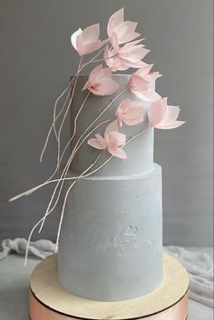 a three tiered cake with pink flowers on top and silver icing in the middle