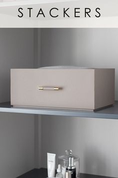 the shelves in this bathroom are organized with white boxes and gold handles, along with toiletries