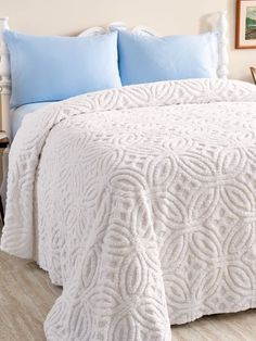 a white bedspread with blue pillows on it