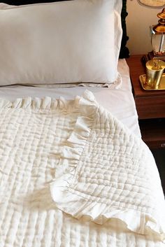 an unmade bed with white sheets and pillows