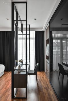 a bedroom with black and white decor, wood flooring and glass partitions to divide it from the room