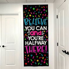 a black and pink wall hanging on the side of a white door in a hallway