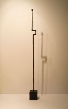 a tall metal pole sitting on top of a white floor next to a lamp shade