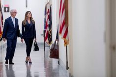 two people walking down a hallway with flags in the background