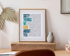 a framed book page sitting on top of a wooden table next to a vase and plant