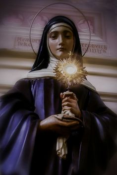 the immaculate mary statue is shown in front of a building with a light shining from her hand