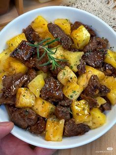 a white bowl filled with meat and potatoes