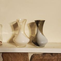 three vases sitting on top of a white shelf