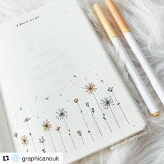 two pens sitting on top of an open notebook next to each other, with flowers drawn on the pages