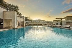 an outdoor swimming pool with lounge chairs and umbrellas on the side at sunset or dawn