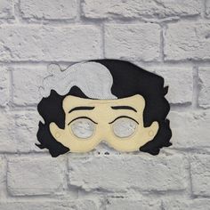 a white brick wall with a black and yellow mask on it