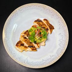 a white plate topped with grilled chicken covered in lettuce and tomato sauce