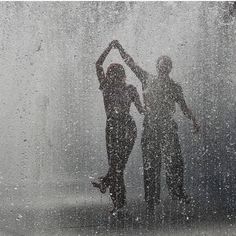 two people are standing in the rain with their hands up to their heads and arms