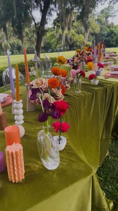 a long table is set up with candles and vases filled with colorful flowers on it