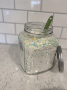 a glass jar filled with yellow and blue sprinkles on top of a counter