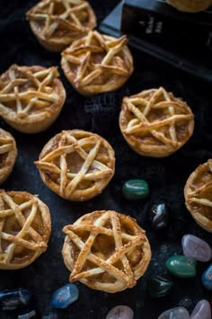 several small pies are arranged on a black surface with rocks and stones around them