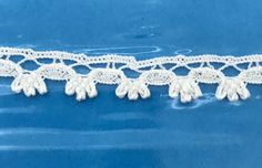 white crocheted lace with tassels on blue background