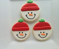 three decorated snowman cookies sitting on top of a white plate