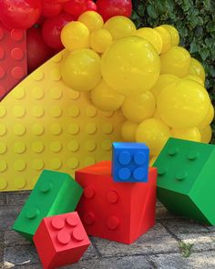 three lego blocks sitting next to each other on the ground with balloons in the background