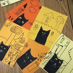 four pieces of paper with black cats on them sitting on top of a wooden table