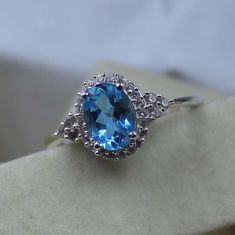 an oval blue topaz ring sits on a piece of white gold with diamonds around it