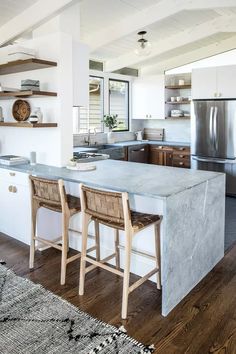 a kitchen with two stools next to an island in the middle of the room