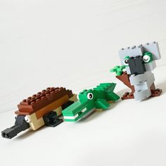 three lego animals that are standing next to each other on a white surface, one is holding an alligator's head and the other has its mouth open