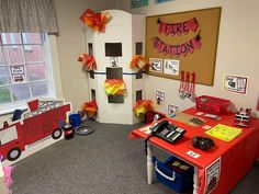 a fire station themed classroom with red desks and decorations on the walls, around a fire truck