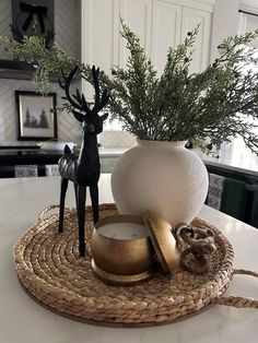 a white vase sitting on top of a table next to a deer figurine