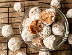 a glass bowl filled with powdered sugar covered donuts