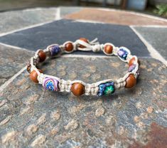 a close up of a bracelet with beads on a stone surface in front of a rock