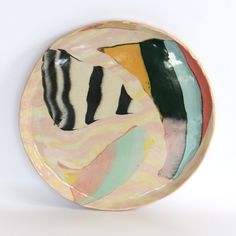 a plate that has been painted with different colors and shapes on it's surface