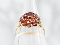 This yellow gold garnet cluster ring is a stunning addition to any jewelry collection. It features gorgeous garnets set in a cluster design, creating a beautiful and timeless piece. Crafted in yellow gold, this ring is a perfect balance of elegance and sophistication. Elevate your style with this luxurious ring.Metal: 18K Yellow GoldGem: GarnetsGem Measurements: 4.7 mm, RoundRing Size: 7Marks: "<750>" Stamped on the inside band Cluster Design, Ring Metal, Cluster Ring, Elevate Your Style, Timeless Pieces, Garnet, Halo, Jewelry Collection, Yellow Gold